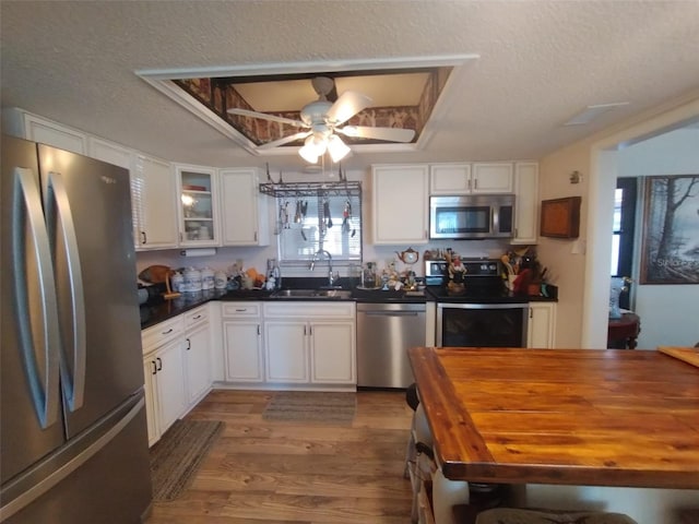 kitchen featuring wood-type flooring, sink, a textured ceiling, white cabinetry, and stainless steel appliances