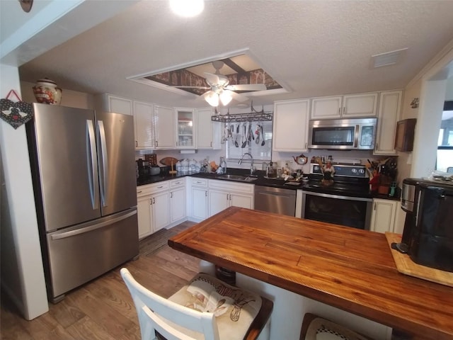 kitchen with ceiling fan, appliances with stainless steel finishes, white cabinetry, light hardwood / wood-style flooring, and sink