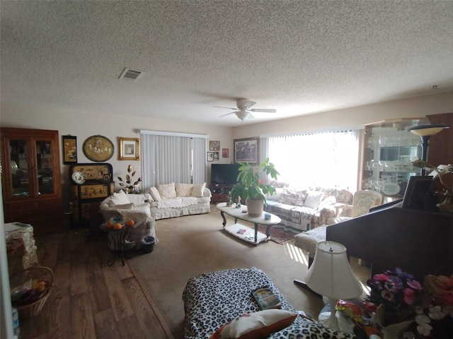 living room featuring ceiling fan, wood-type flooring, and a textured ceiling