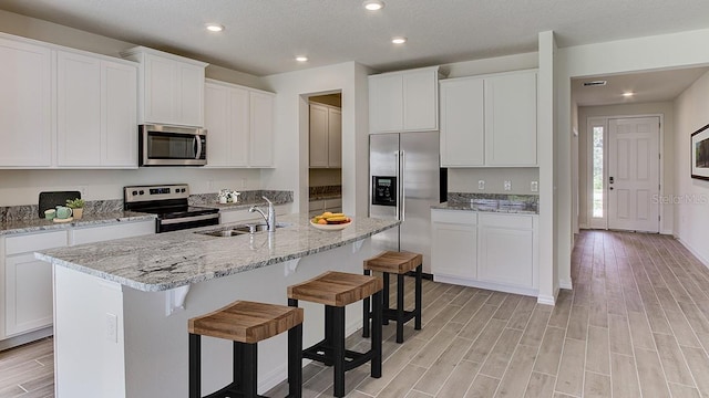 kitchen featuring light hardwood / wood-style floors, stainless steel appliances, sink, and an island with sink