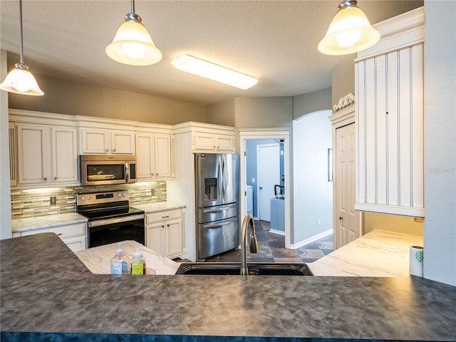 kitchen with pendant lighting, sink, white cabinets, backsplash, and stainless steel appliances