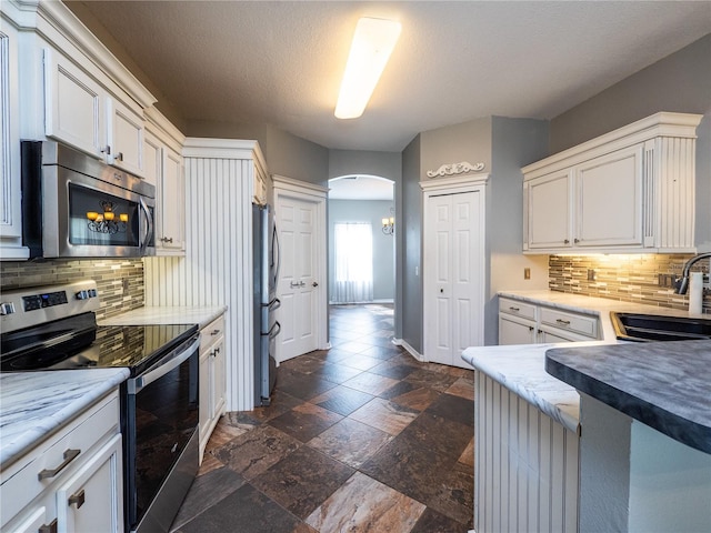 kitchen featuring stainless steel appliances, white cabinetry, sink, and decorative backsplash