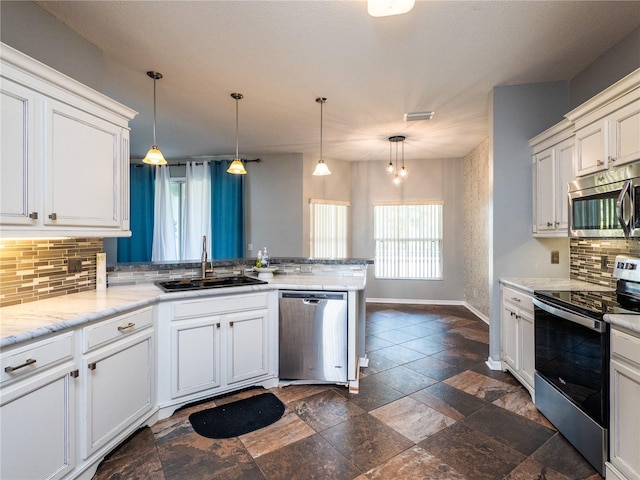 kitchen with pendant lighting, sink, backsplash, and appliances with stainless steel finishes