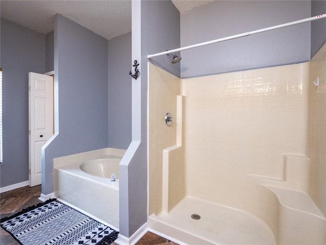 bathroom with shower with separate bathtub and a textured ceiling