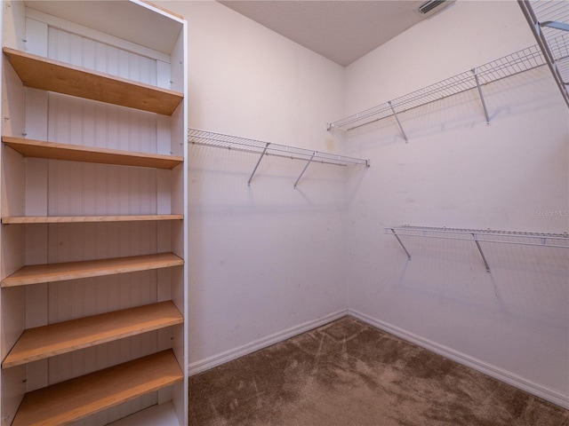 spacious closet featuring dark carpet