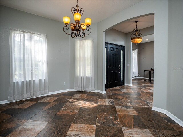 12805 SW 64th Ln, Ocala, FL 34481 - entryway featuring stone tile flooring, arched walkways, baseboards, and a chandelier