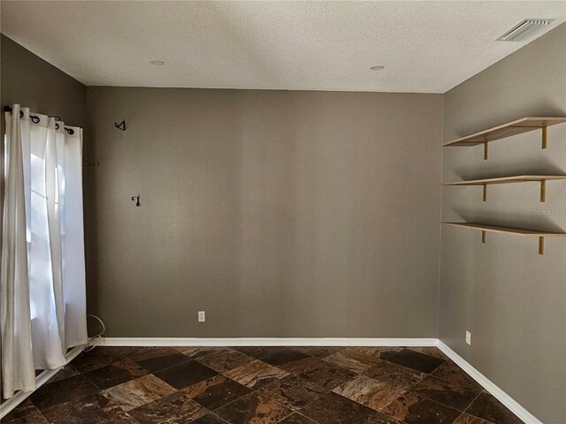 12805 SW 64th Ln, Ocala, FL 34481 - unfurnished room with baseboards, dark stone finish flooring, and a textured ceiling