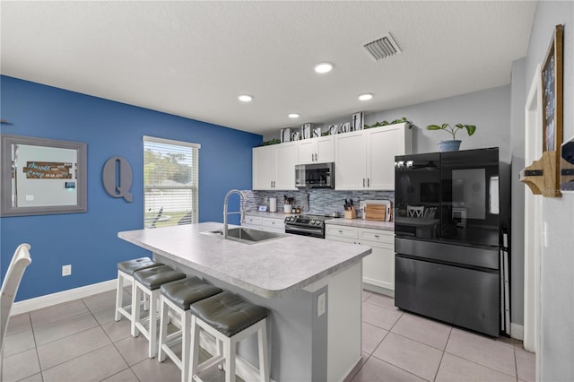 kitchen featuring white cabinets, appliances with stainless steel finishes, a kitchen breakfast bar, a kitchen island with sink, and sink