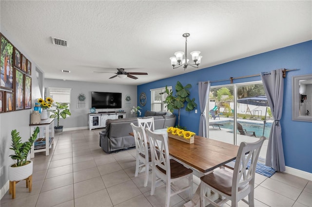 tiled dining area with a textured ceiling and ceiling fan with notable chandelier