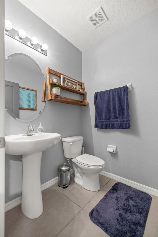 bathroom featuring toilet, a textured ceiling, and tile patterned flooring