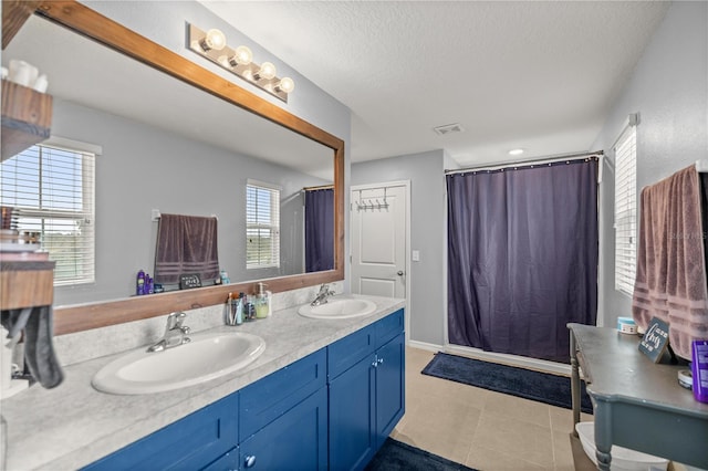 bathroom with vanity, a shower with curtain, a textured ceiling, and tile patterned floors