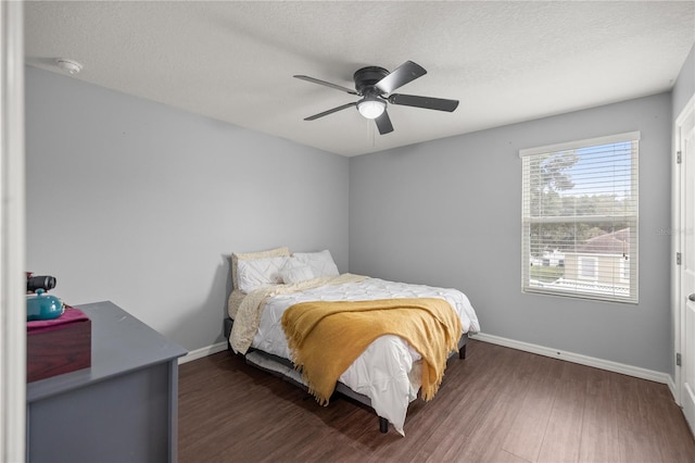 bedroom with dark wood-type flooring, a textured ceiling, and ceiling fan