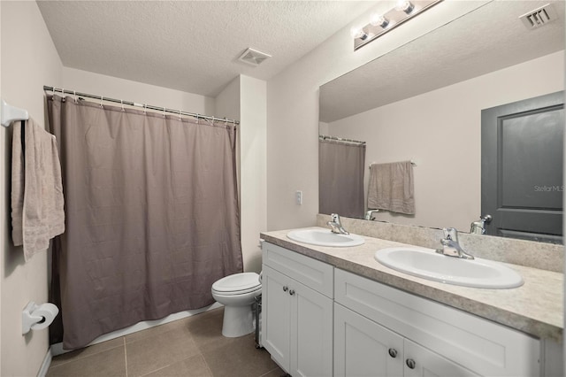 bathroom with a textured ceiling, toilet, tile patterned floors, walk in shower, and vanity