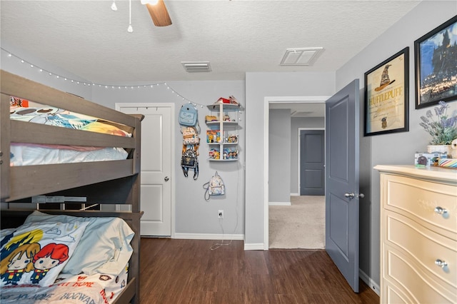 bedroom with dark wood-type flooring, a textured ceiling, and ceiling fan