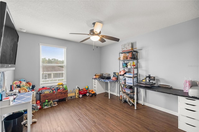 recreation room featuring a textured ceiling, dark wood-type flooring, and ceiling fan