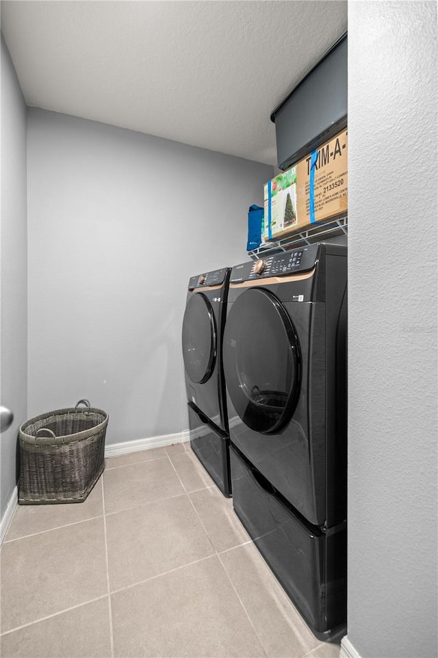 clothes washing area with washer and dryer, a textured ceiling, and tile patterned flooring