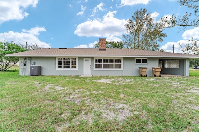 rear view of house with central AC unit and a lawn