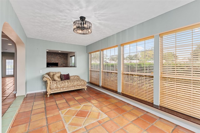 sunroom / solarium featuring an inviting chandelier and a fireplace