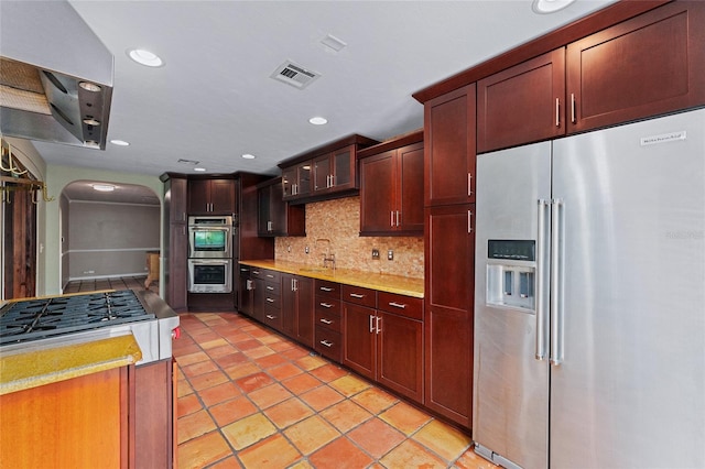 kitchen with appliances with stainless steel finishes, tasteful backsplash, sink, and light tile patterned floors