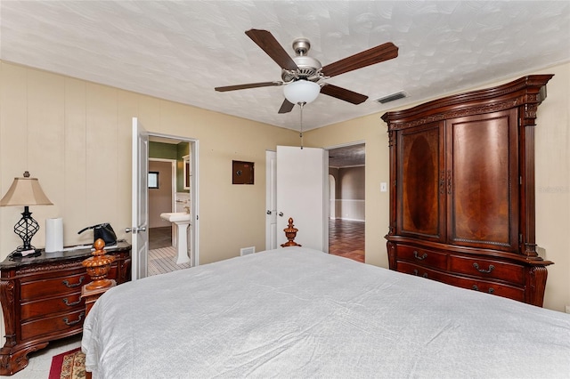 bedroom featuring ensuite bath, a textured ceiling, and ceiling fan