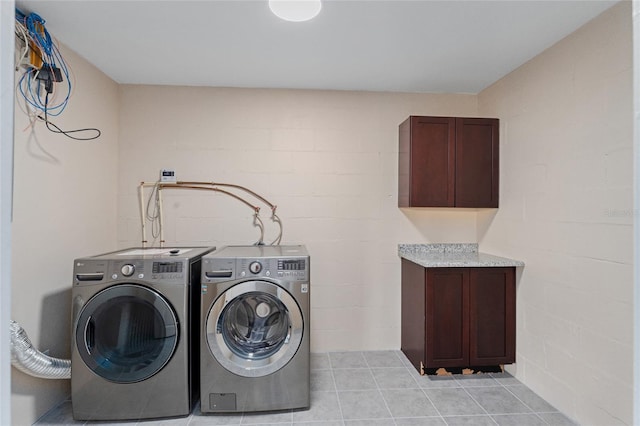 laundry room with light tile patterned floors, cabinets, and separate washer and dryer