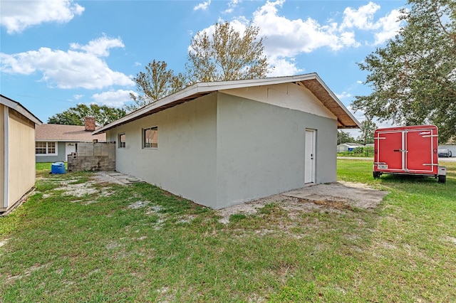 rear view of house featuring a storage shed and a lawn