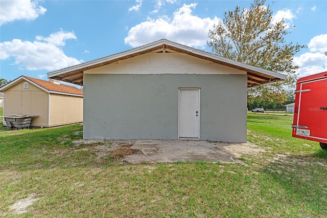 back of house featuring a storage unit and a lawn