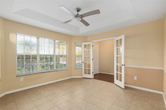 tiled spare room with french doors, ceiling fan, and a raised ceiling