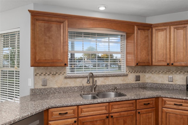 kitchen with sink, light stone counters, and tasteful backsplash