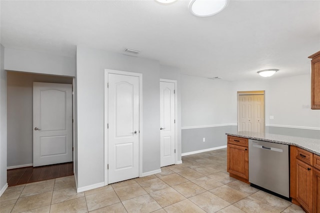 kitchen featuring light tile patterned floors, light stone countertops, and dishwasher