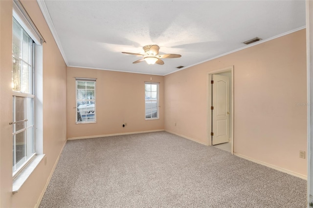 carpeted spare room featuring ceiling fan, ornamental molding, and a wealth of natural light