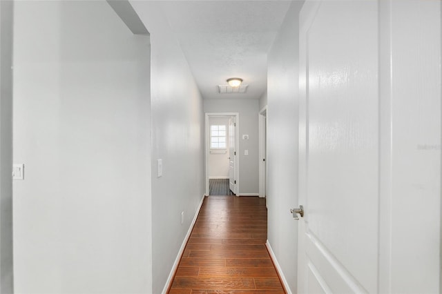 hallway featuring a textured ceiling and dark hardwood / wood-style floors