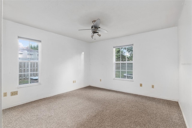 carpeted spare room featuring a wealth of natural light and ceiling fan