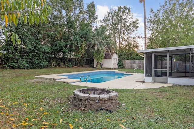 view of pool featuring a sunroom, a storage shed, an outdoor fire pit, and a lawn