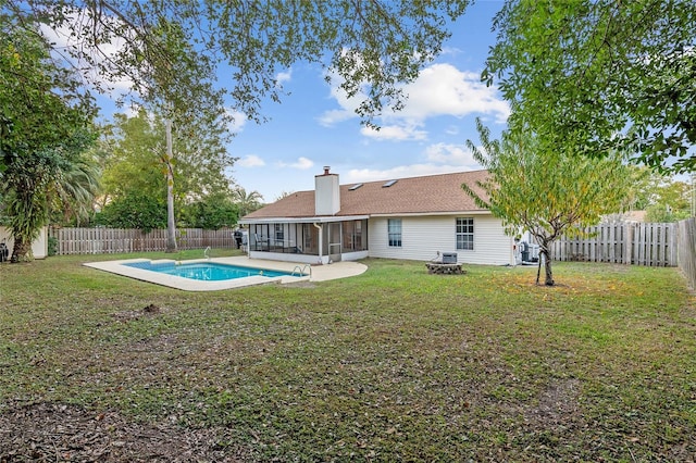 back of house featuring a fenced in pool, a yard, an outdoor fire pit, and a sunroom