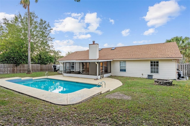 view of swimming pool with an outdoor fire pit, a lawn, and a sunroom