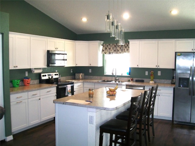 kitchen with hanging light fixtures, appliances with stainless steel finishes, white cabinetry, sink, and a center island