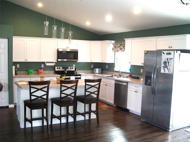 kitchen with white cabinets, appliances with stainless steel finishes, vaulted ceiling, sink, and decorative light fixtures