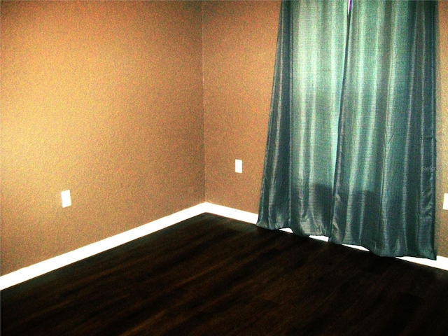 unfurnished room with dark wood-type flooring