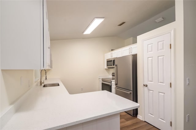 kitchen with sink, kitchen peninsula, white cabinetry, stainless steel appliances, and light hardwood / wood-style flooring