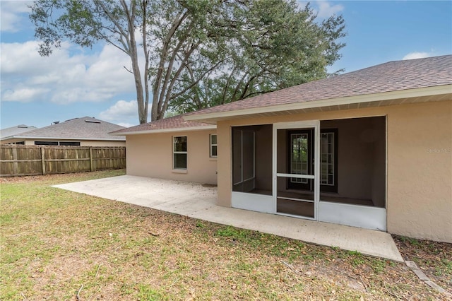 back of property with a patio, a lawn, and a sunroom