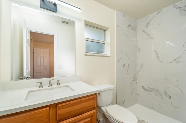 bathroom featuring vanity, toilet, and a tile shower