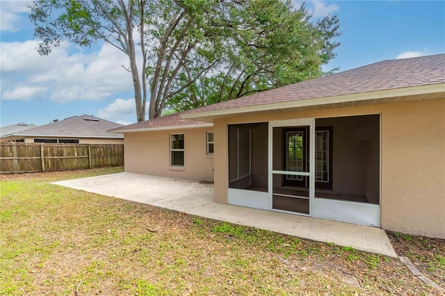 rear view of house with a patio area, a lawn, and a sunroom