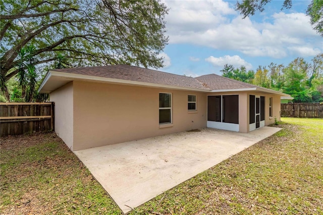 rear view of property featuring a yard, a patio area, and a sunroom