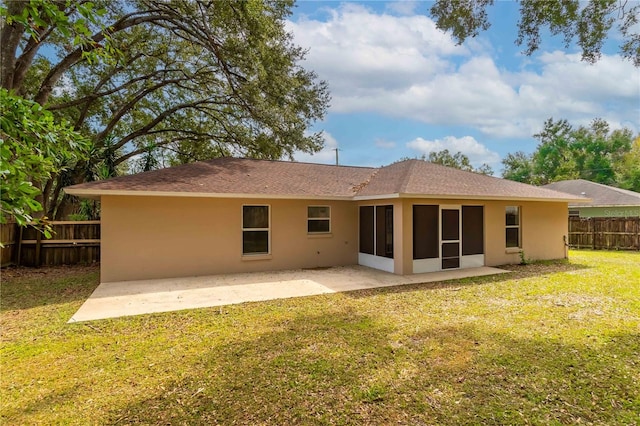 rear view of house featuring a patio area, a lawn, and a sunroom