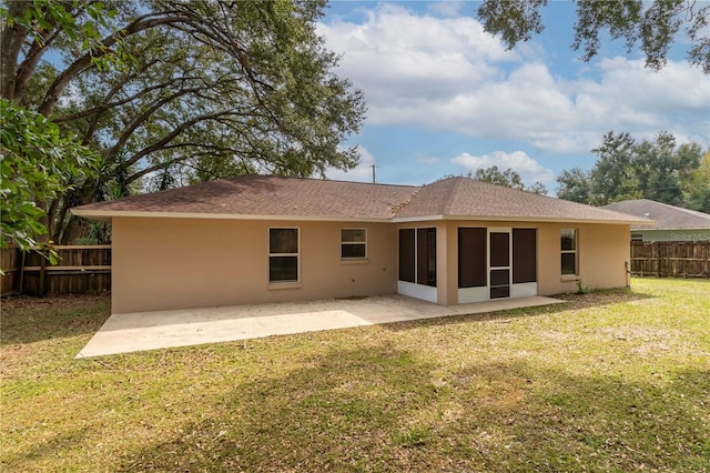 rear view of property featuring a patio, a sunroom, and a lawn