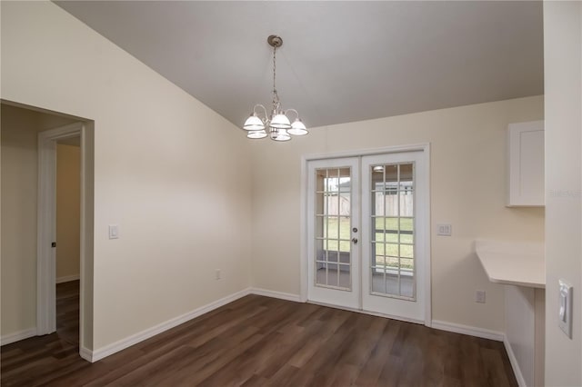 unfurnished dining area featuring vaulted ceiling, a notable chandelier, dark hardwood / wood-style flooring, and french doors