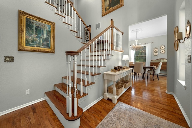 stairway with a notable chandelier, wood-type flooring, and crown molding