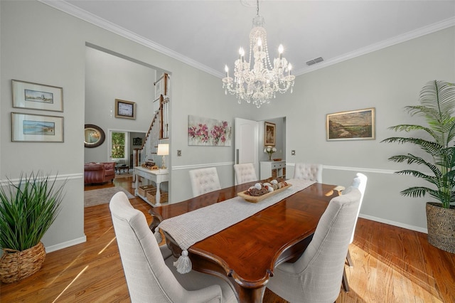 dining room with an inviting chandelier, crown molding, and light wood-type flooring