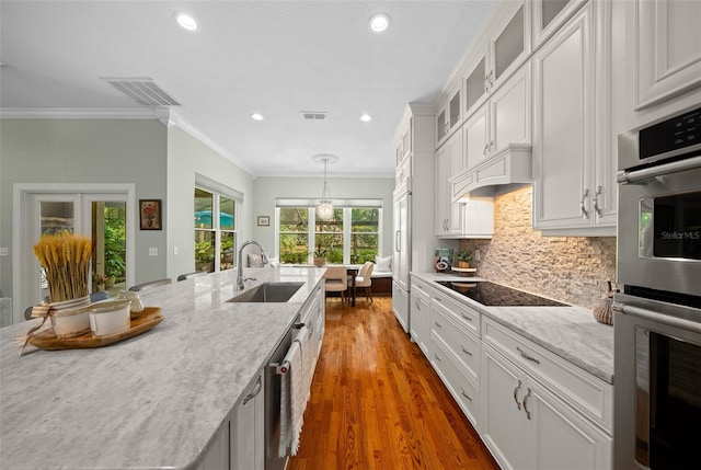 kitchen featuring white cabinetry, wood-type flooring, stainless steel appliances, sink, and decorative light fixtures